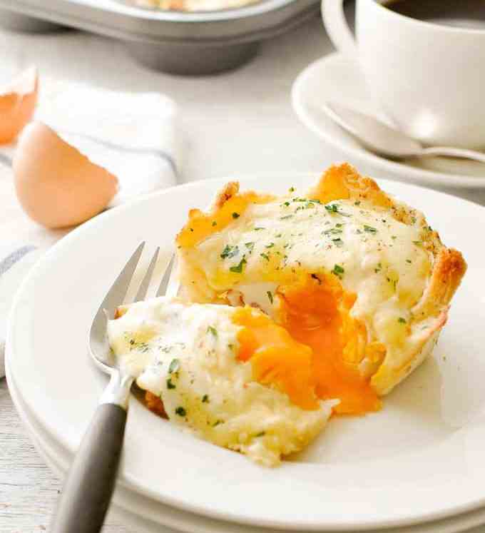 松饼罐头早餐Croque Madame Toastie杯放在一个白色盘子上，切开，流出流淌的蛋黄。