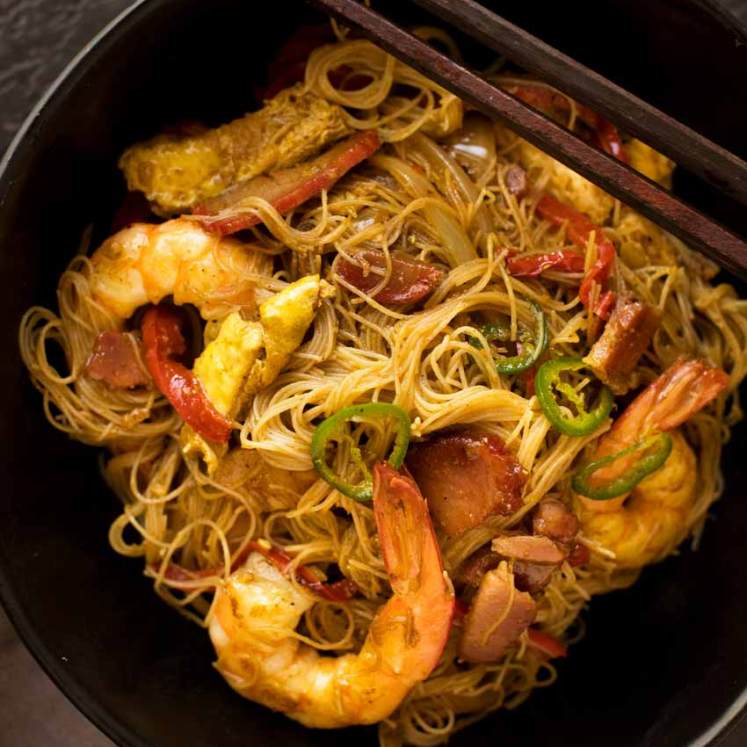 头顶的照片，新加坡面在一个黑色的碗里，筷子放在边上，准备吃。