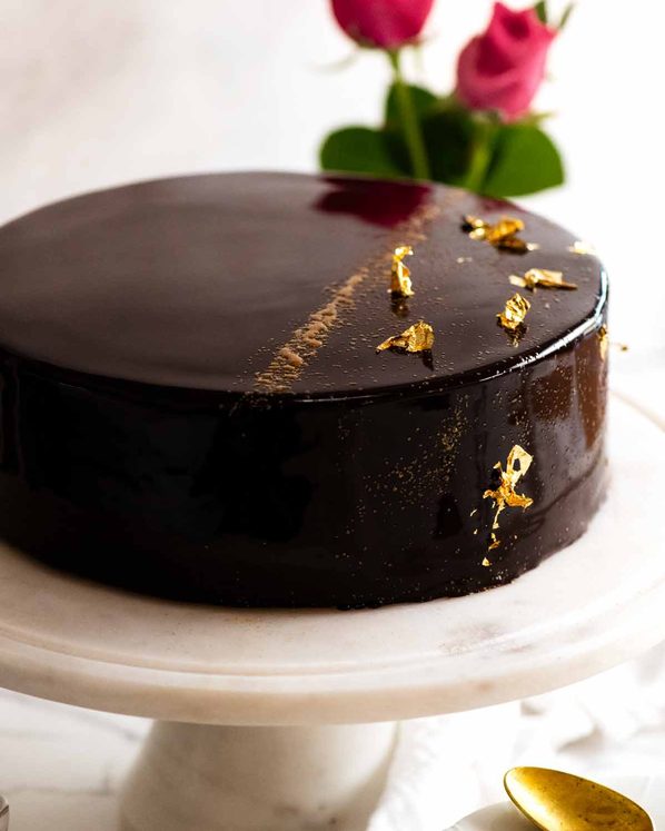 巧克力镜釉蛋糕放在蛋糕盘上，即可享用gydF4y2Ba