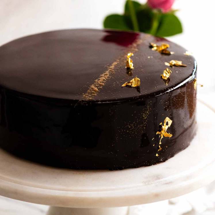 巧克力镜釉蛋糕放在蛋糕盘上，准备上桌