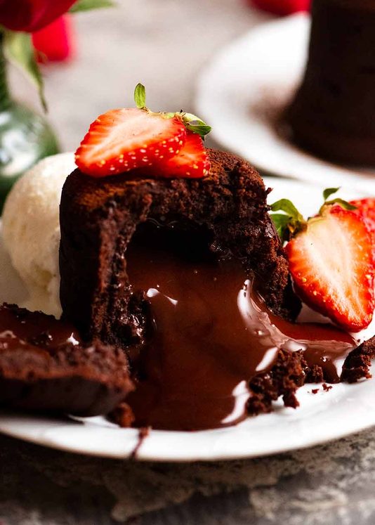 熔融巧克力蛋糕的特写，巧克力熔岩倾泻而出，用草莓和一勺冰淇淋装饰gydF4y2Ba