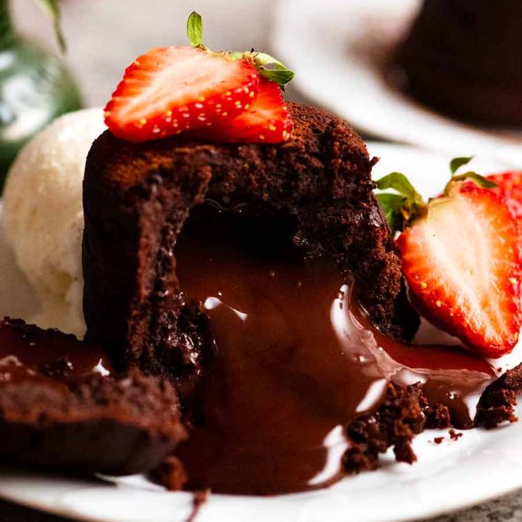 关闭熔化巧克力蛋糕用倾吐的巧克力熔岩，装饰用草莓和冰淇凌瓢